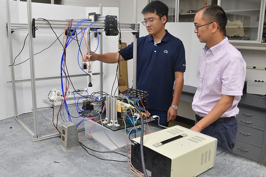 Long He (right) and visiting doctoral student Mingsen Huang testing the robotic mushroom picker in the lab. - Photo: Penn State