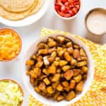 spicy potato taco ingredients - tortillas, cheese, lettuce, tomatoes, potatoes and chipotle sauce