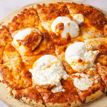 Pizza topped with burrata cheese and sun dried tomato