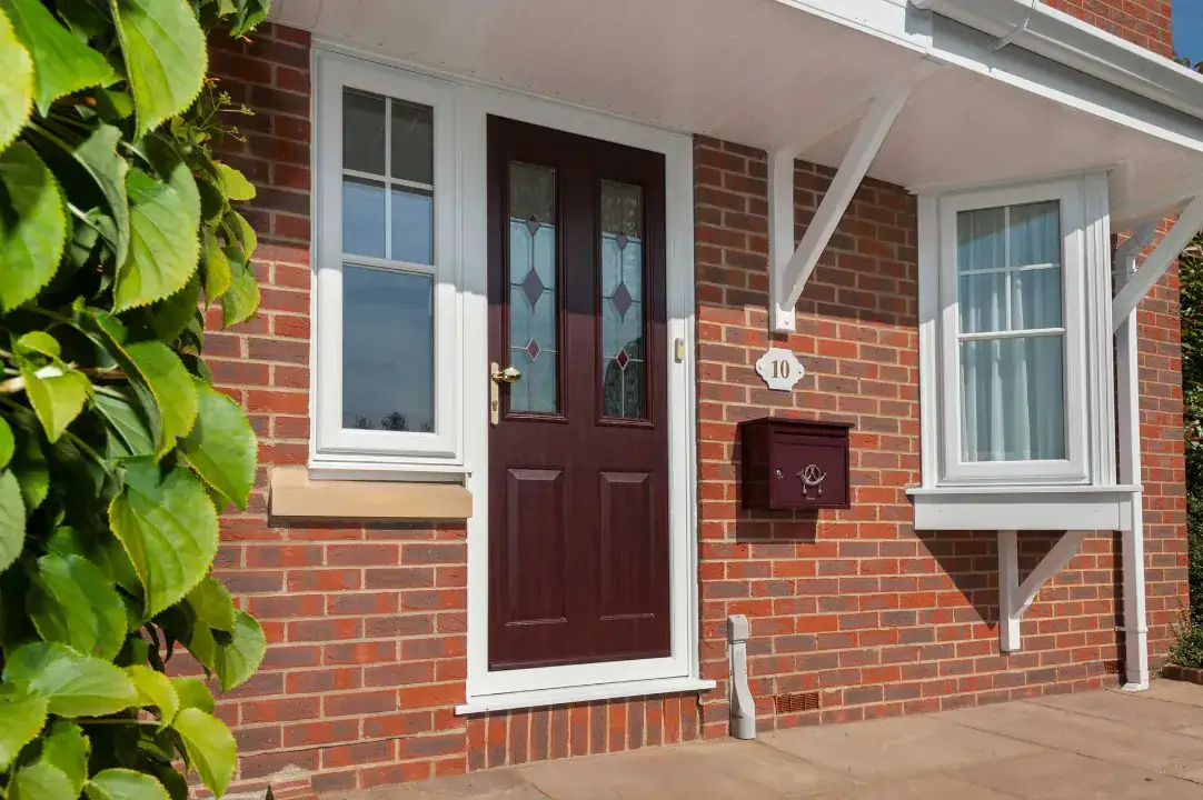 Red uPVC entrance door with decorative glazing fitted to a brick home