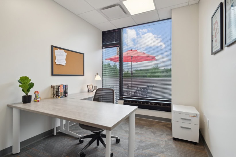Modern office workspace with natural light and a cozy outdoor view, ideal for productivity and business meetings.