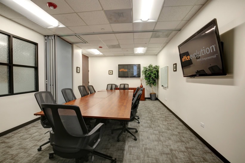 Modern office conference room with meeting table and TV display for business collaboration.