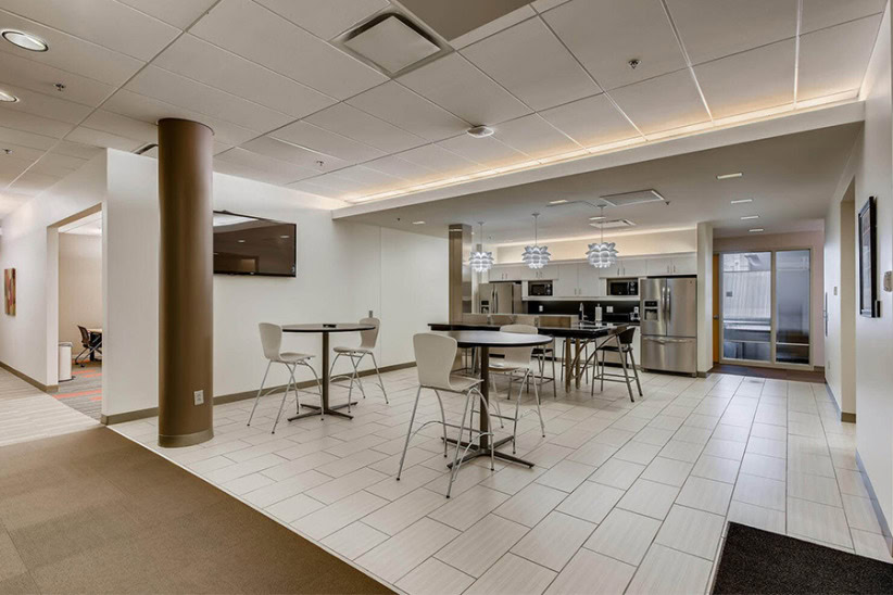 Modern office lounge with stylish seating and kitchen area, ideal for collaboration and relaxation.