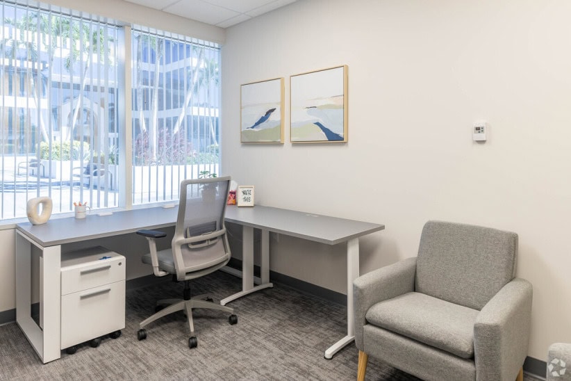 Modern office workspace with large window and minimalist decor.