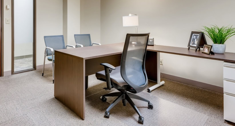 Modern corporate office space with a large desk, ergonomic chair, and work area at Office Evolution.
