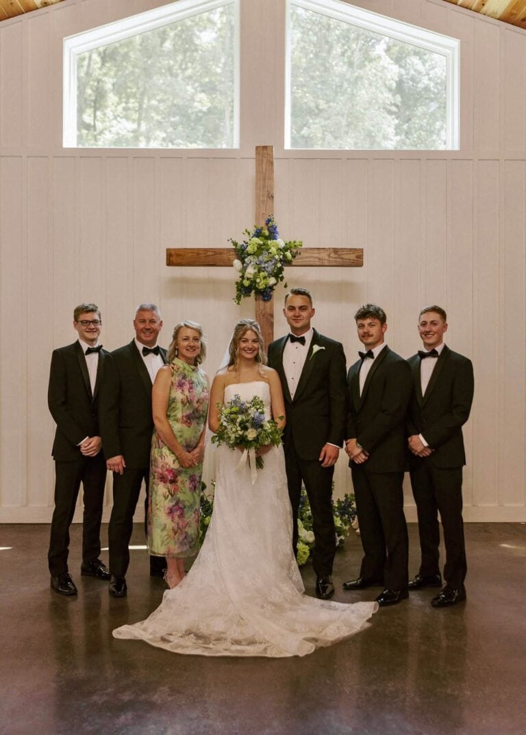 Calla and Ryan with family in front of the flower-draped wooden cross in the Romaine Valley chapel