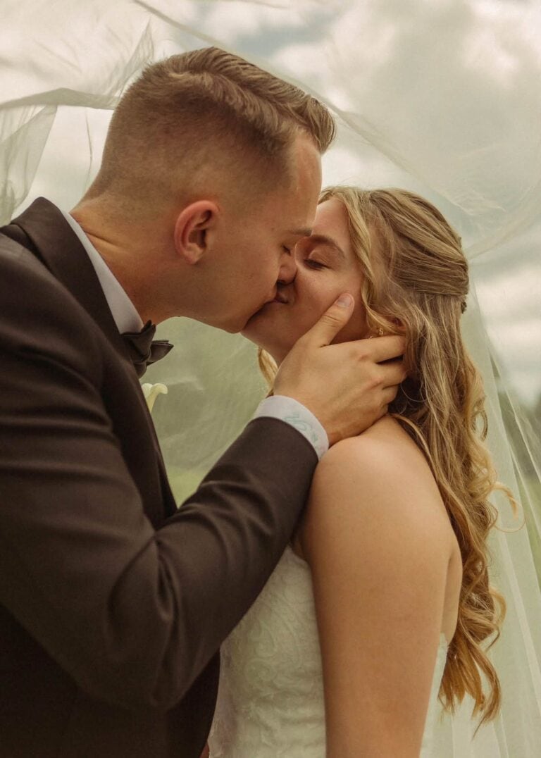 Calla and Ryan share a kiss under her veil on the grounds at Romaine Valley Weddings & Events