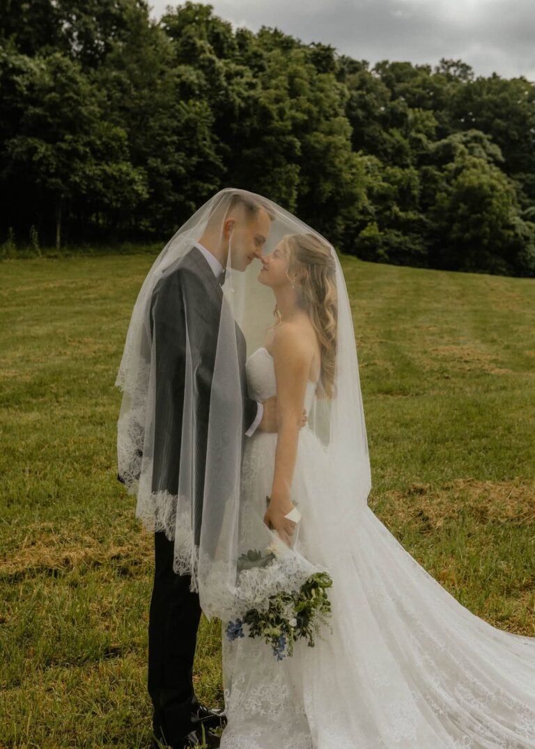 Calla and Ryan stand nose to nose under her lace veil in the field at Romaine Valley