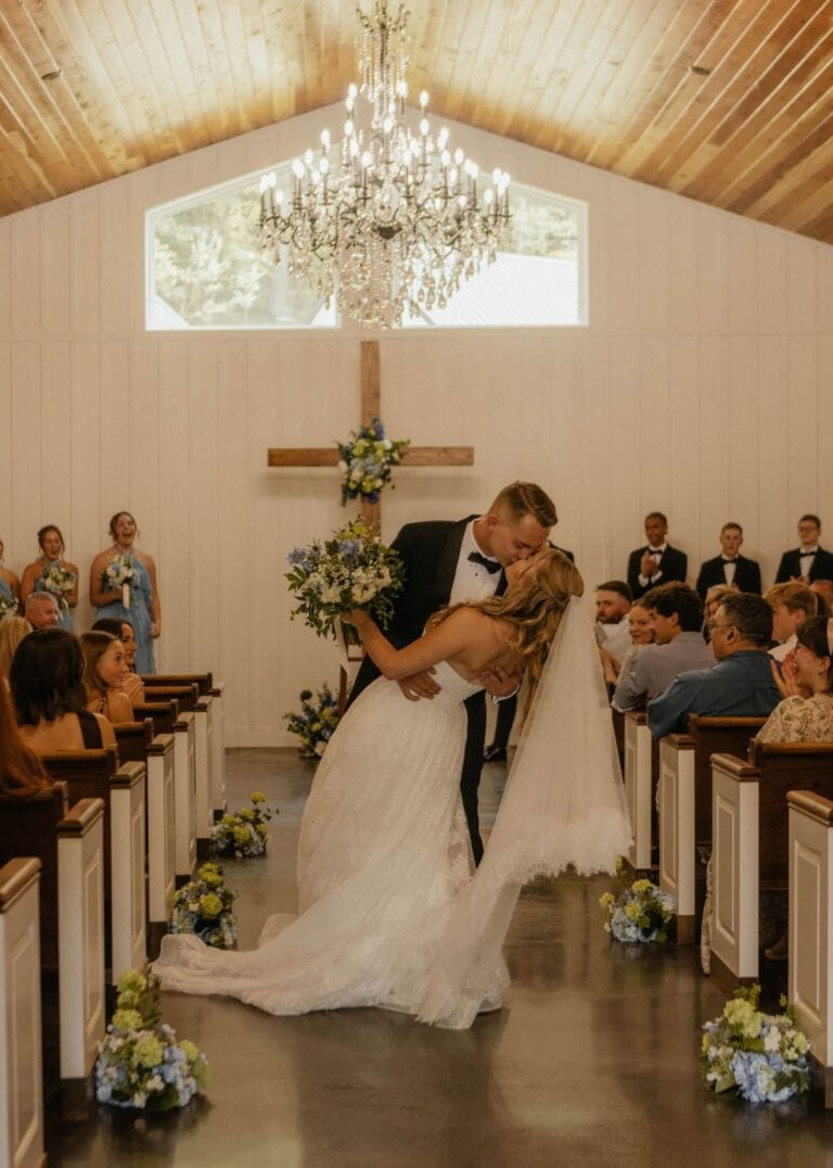 Ryan dips Calla for a kiss in the aisle of the Romaine Valley chapel beneath the crystal chandelier