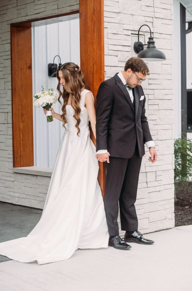 Erina and Nick hold hands and pray on either side of a wall before their ceremony at Romaine Valley