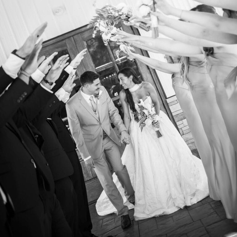 Noe and Grace walk out under raised arms after their ceremony at Romaine Valley