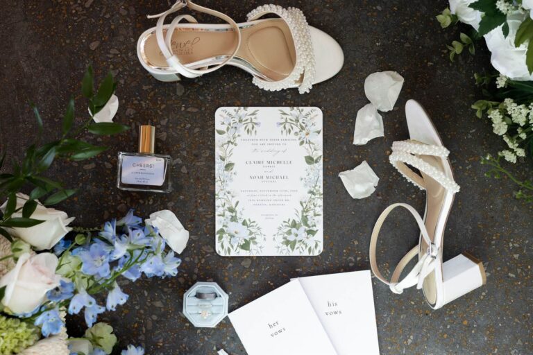 Wedding invitation, pearl heels, rings and vow books for Noah and Claire at Romaine Valley in Fenton, MO