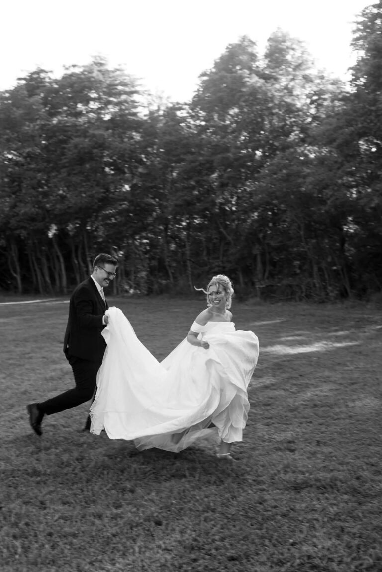 Black and white photo of Noah and Claire running across the lawn at Romaine Valley Weddings & Events