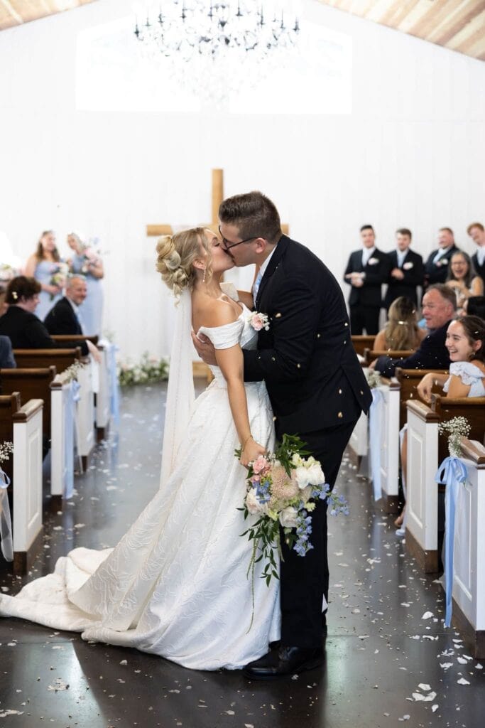 Noah and Claire kiss in the aisle of the Romaine Valley chapel as guests toss petals