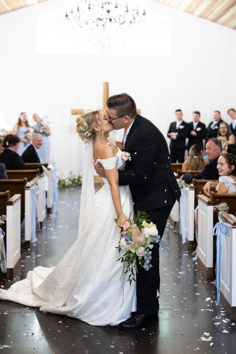 Noah and Claire kiss in the aisle of the Romaine Valley chapel as guests toss petals