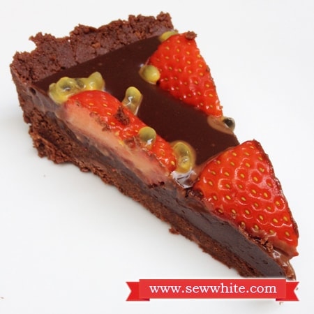 A slice of chocolate tart with strawberries and passion fruit