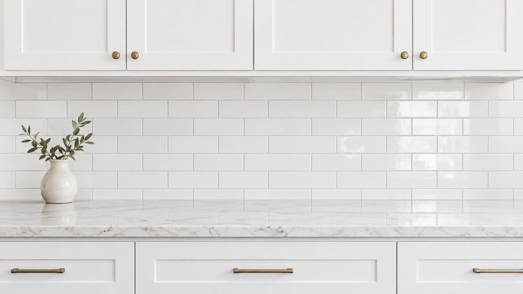 A modern kitchen interior featuring a clean white marble countertop and a classic white subway tile backsplash.