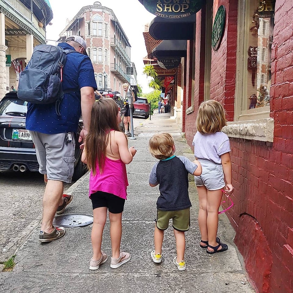 A colorful street scene in Eureka Springs with children and an adult exploring local shops.
