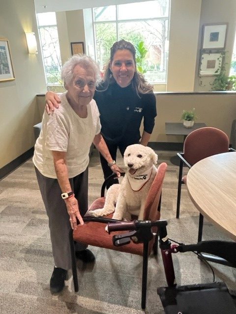 Resident enjoying a pet therapy visit with a therapy dog at Two Neptune Drive.