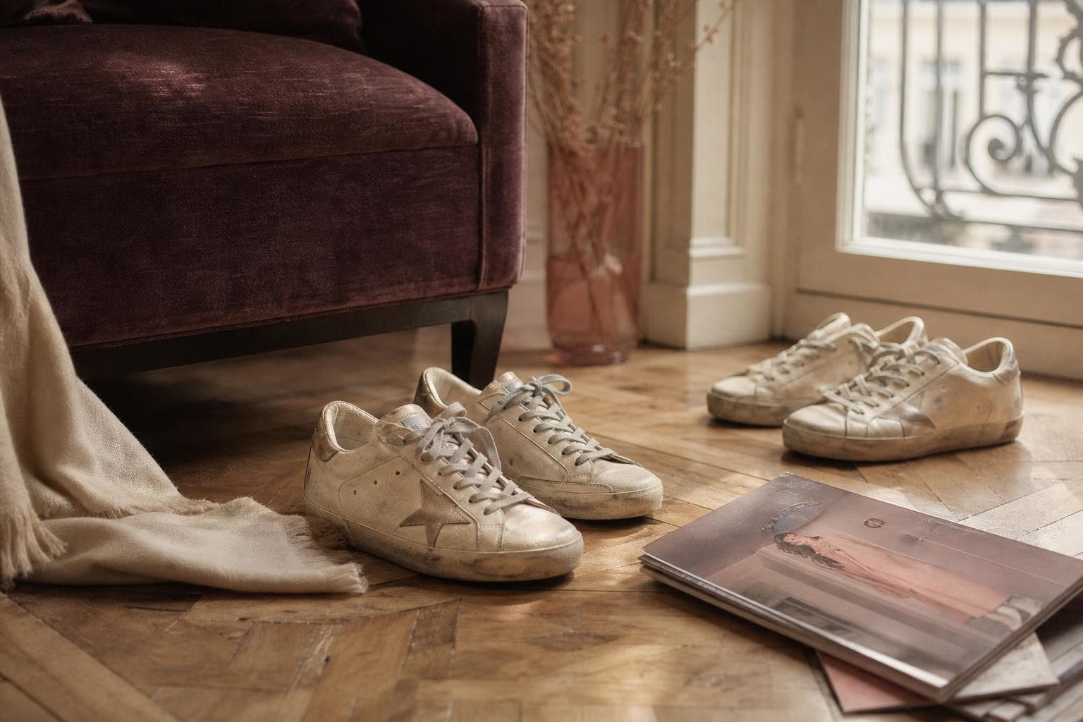 Baskets Golden Goose vieillies en cuir crème, posées près d'un fauteuil en velours prune dans un intérieur annécien chaleureux
