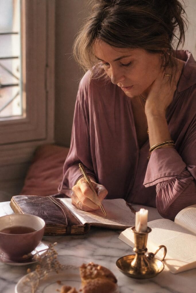 Rubrique Développement personnel , une femme écrit dans un article en cuir, livre de philosophie ouvert, bougie en laiton
