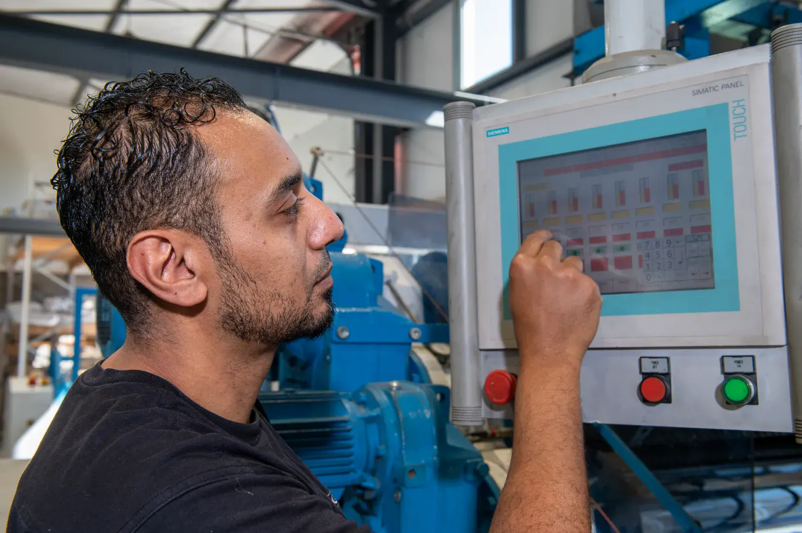 Worker using a touchscreen control panel on industrial machinery.