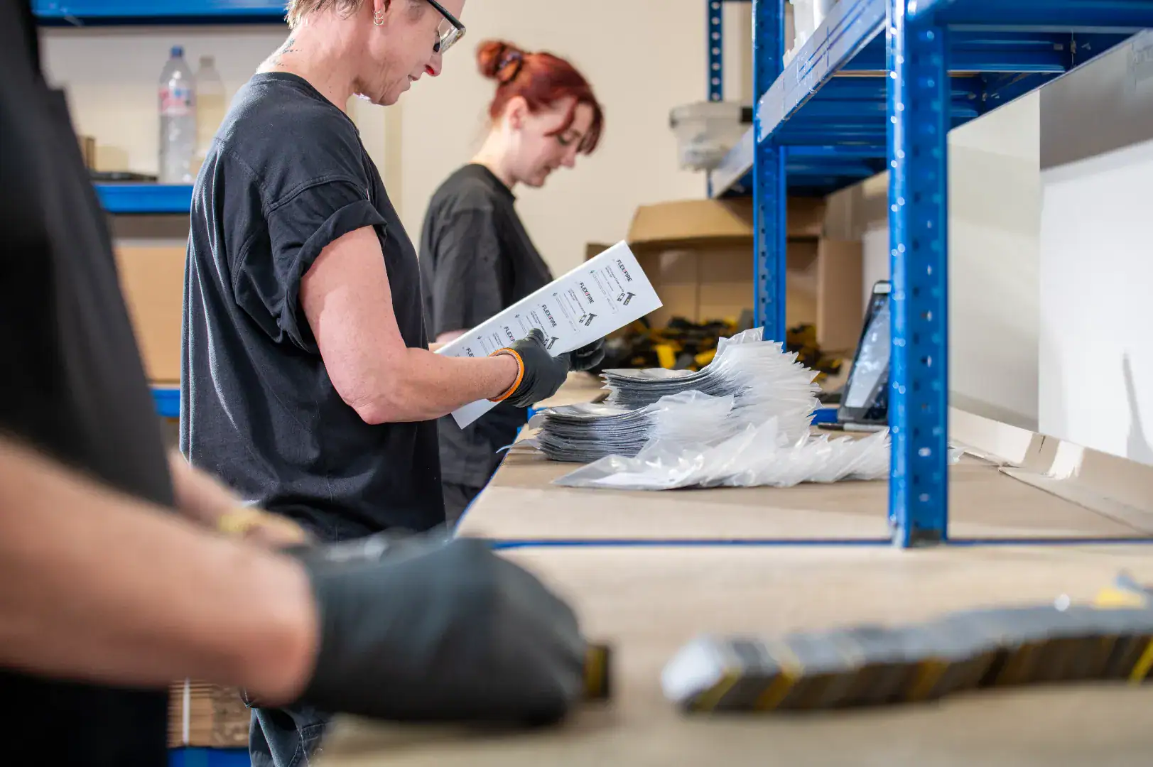 Workers packing and checking material components on a workshop bench.