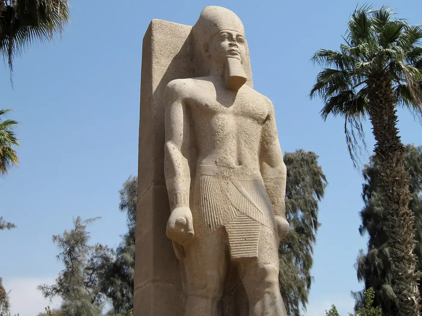 Standing pharaoh statue among palms at Mit Rahina