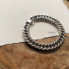 Silver chain bracelet on textured paper background.