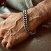 Man wearing silver chain bracelet on wrist.