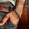 Hand wearing silver chain bracelet and textured jeans.