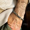 Man wearing intricate silver bracelet on wrist.