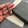 Hand holding Antikuos chain link bracelet on fabric