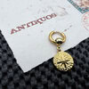 Gold cross coin earring on textured surface