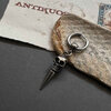 Silver skull earring on paper and stone background.