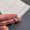 Hand holding a small silver earring on cloth.