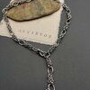 Silver chain necklace on fabric with ANTIKUOS logo.