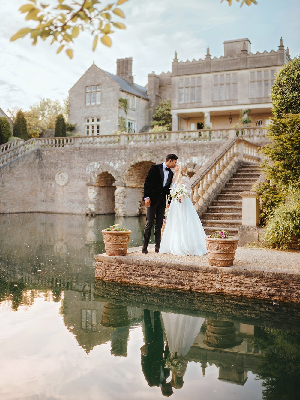 Smart couple on their wedding day, kissing in front of impressive Euridge Manor in the cotswolds. Photo by Joab Smith Wedding Photography