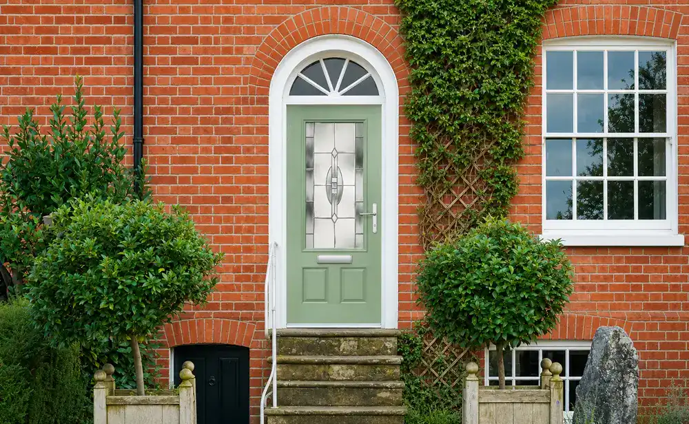 Light green composite front door on a traditional brick home in Aylesbury with decorative glazing and tidy entrance steps
