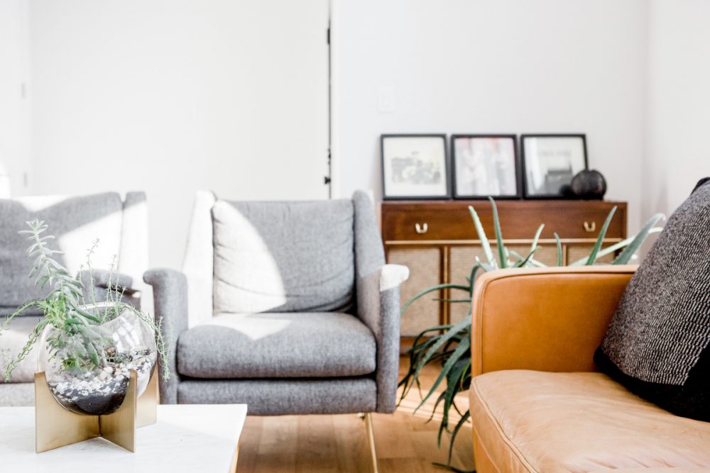 minimalist living room with two small gray accent chairs, coffee table, side table and a few plants