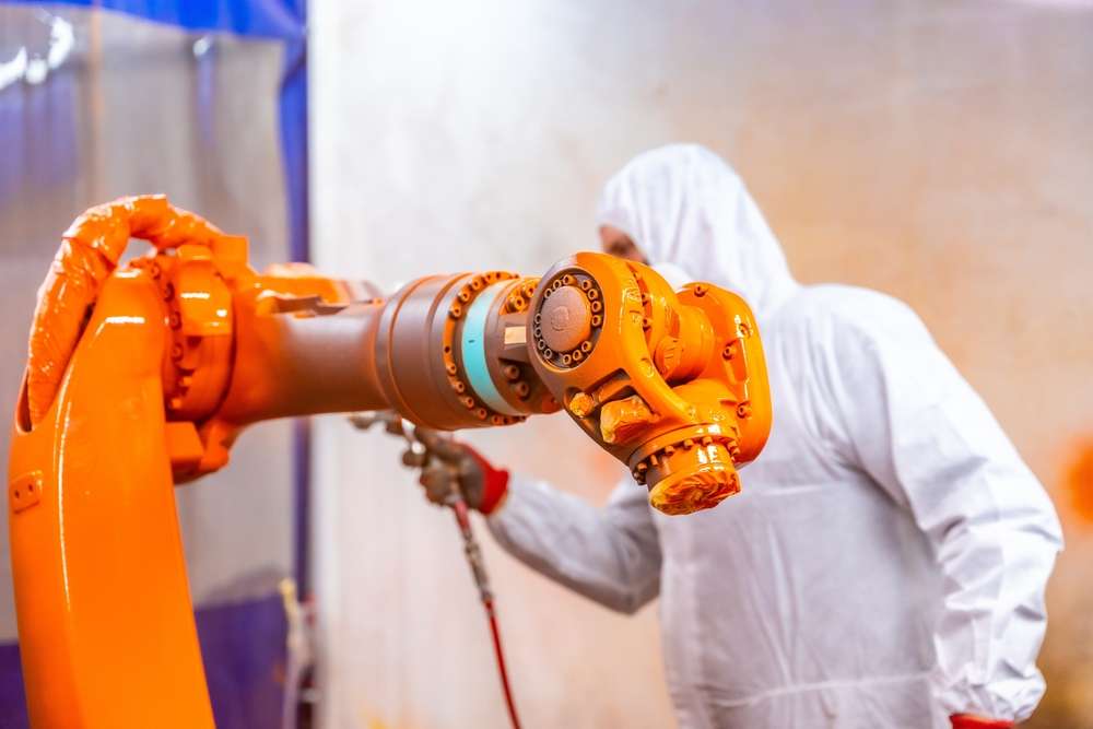 Industrial,Painter,With,Protective,Gear,Painting,A,Robotic,Arm,With