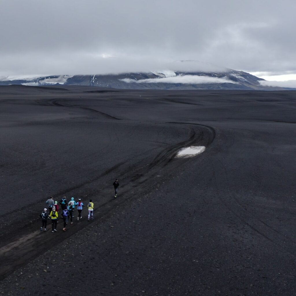 A photograph of some people walking through a dirt track