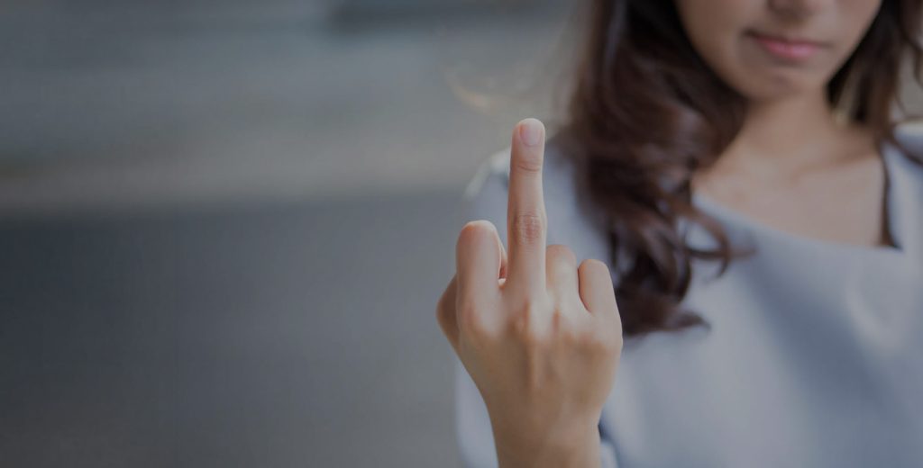 F**k off - junge Frau zeigt ausgestreckten Mittelfinger