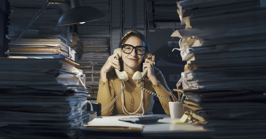 Frau mit 2 Telefonhörern und Aktenordnern -Präkrastination - der Stress alles sofort zu erledigen,