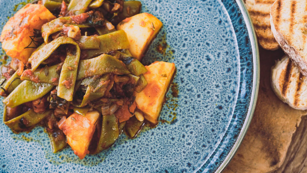 griechische Bohnen in Tomatensoße auf einem Keramikteller