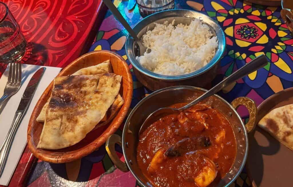Indian curry with rice and naan bread on a colourful table.