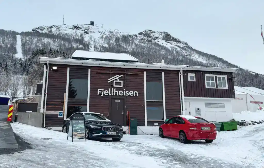 Fjellheisen building in Tromso with snow-covered ground and mountains in the background.