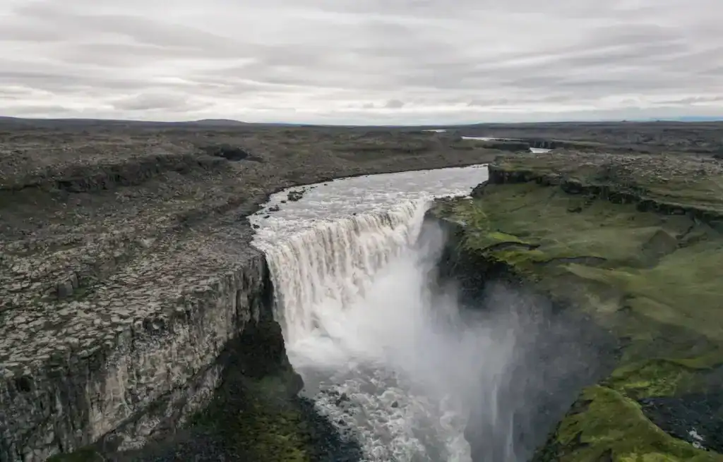 Gullfoss waterfall in Iceland with a wide cascade and mist rising from the river below.