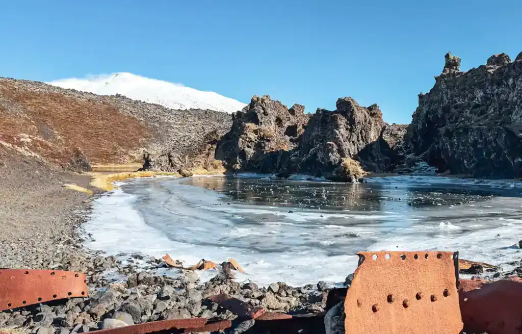 View of Djúpalónssandur beach with rocky formations and snow-capped mountains in the background.