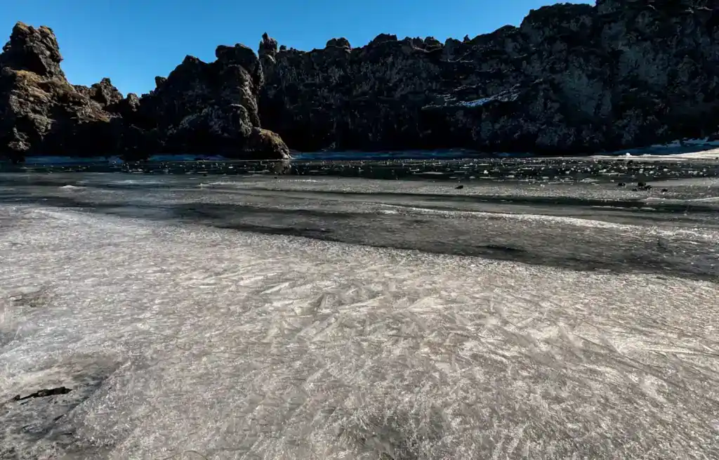 Sandy beach with rocky cliffs and clear blue sky in the background.